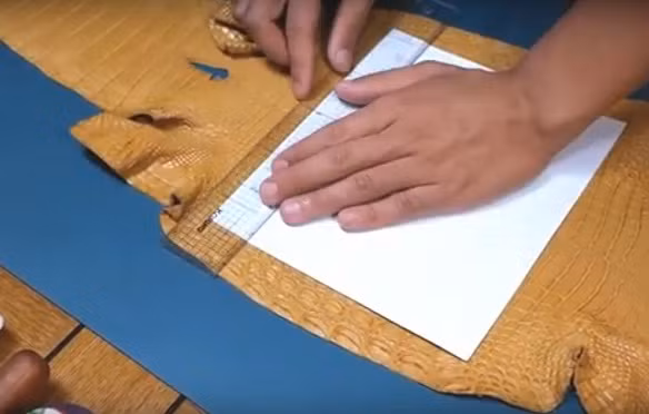 Sau đó, người thợ dùng thước kẻ vẽ lên mặt da theo kích thước chuẩn có sẵn và dùng dao cắt.