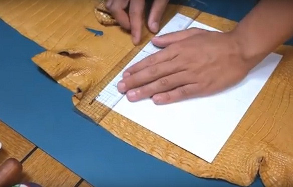 Sau đó, người thợ dùng thước kẻ vẽ lên mặt da theo kích thước chuẩn có sẵn và dùng dao cắt.