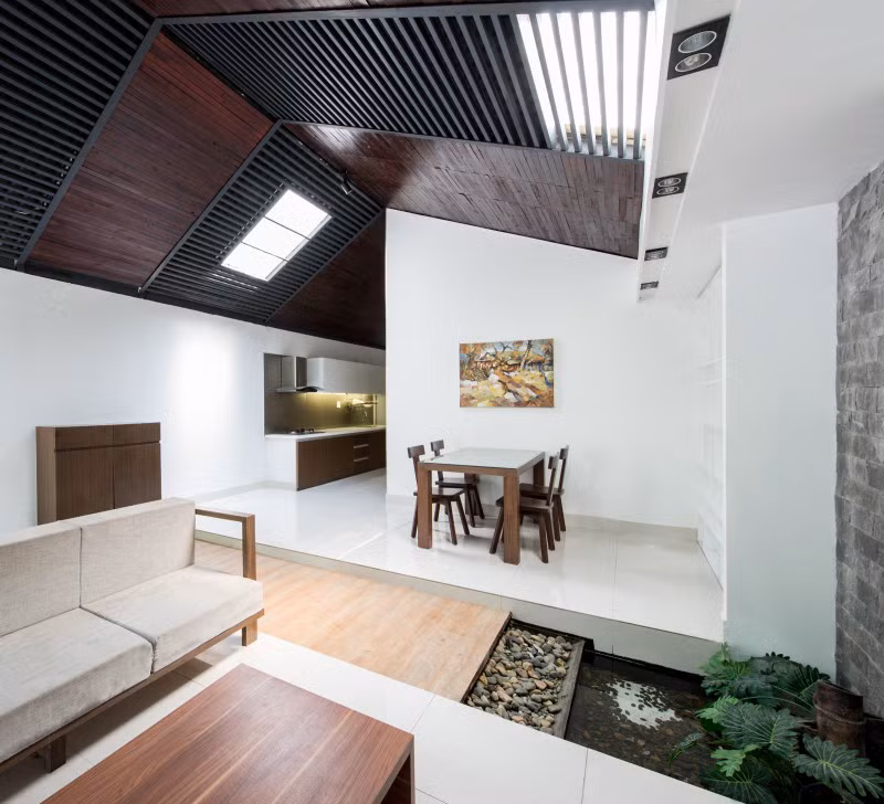 Phòng khách và phòng ăn ngăn cách nhau bằng tiểu cảnh sân vườn với cây xanh, hồ nước nhỏ.