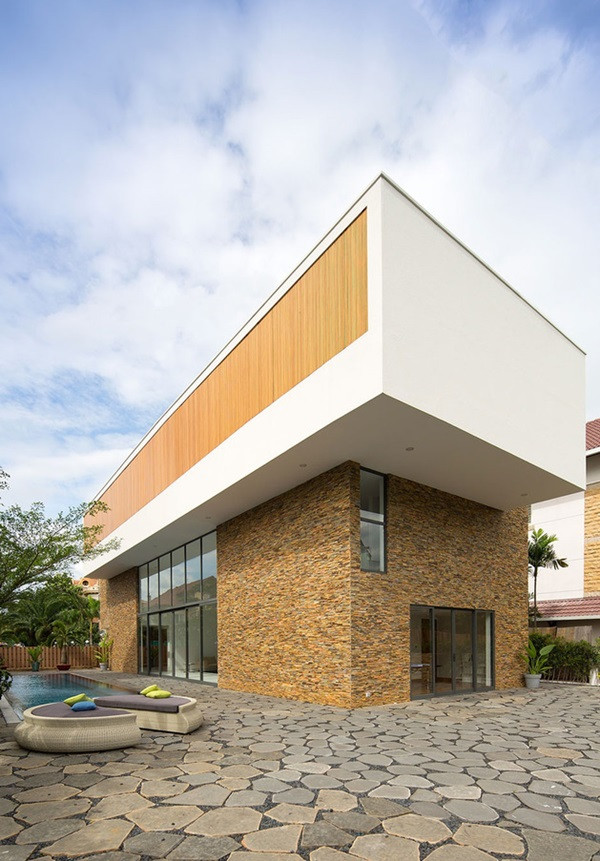 Bên ngoài biệt thự 2 tầng là bể bơi ngoài trời rộng, lát gạch tối màu sang chảnh.