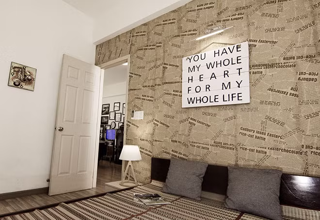 Bức tường đầu giường được trang trí bằng các thanh ván pallet ghép lại với nhau và dán chữ. Nguồn ảnh: Cát Mộc.