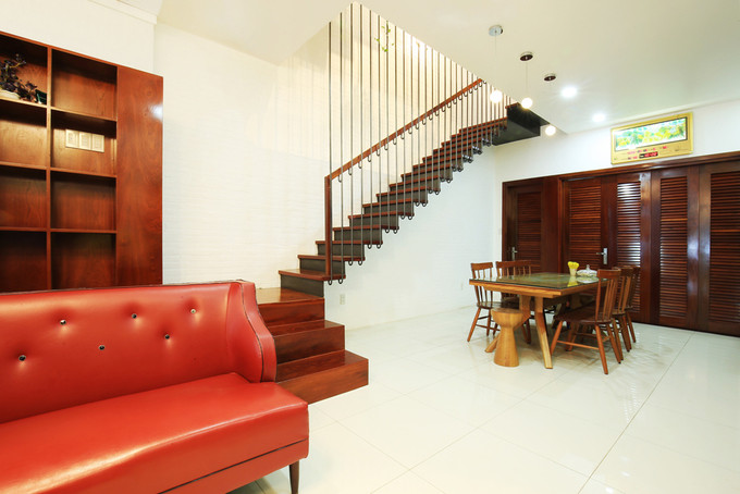 Phòng khách đơn giản với sofa da màu đỏ. Kế đến là khu vực bàn ăn ở trong góc.