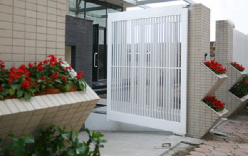 Cổng rào biệt thự 3 tầng sử dụng gam màu trắng sang trọng xen lẫn bồn hoa tươi.