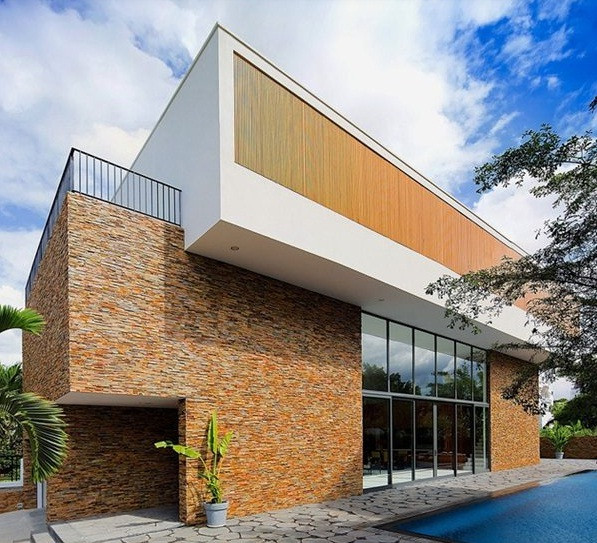 Được tạo thành từ hai khối vuông vức, bên ngoài ngôi biệt thự là một bể bơi rộng, quanh bờ lát gạch màu trung tính. Ảnh: Xaydungkbs.