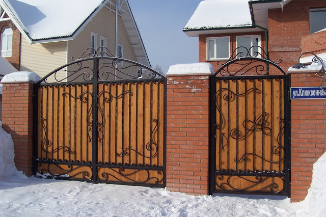 Cổng gỗ đẹp mắt với khung sắt tạo hoa văn. Ảnh: Skyhome.