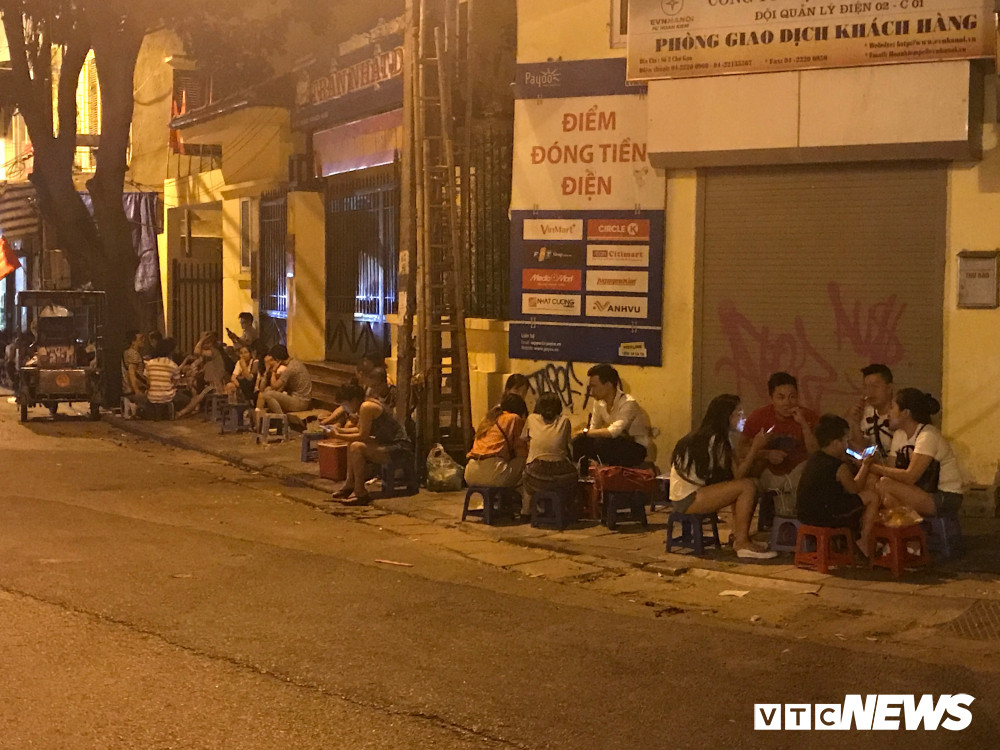 Một quán trà đá nườm nượp khách ngồi dọc vỉa hè vào buổi tối.