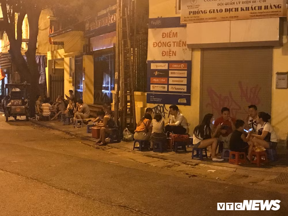 Một quán trà đá nườm nượp khách ngồi dọc vỉa hè vào buổi tối.