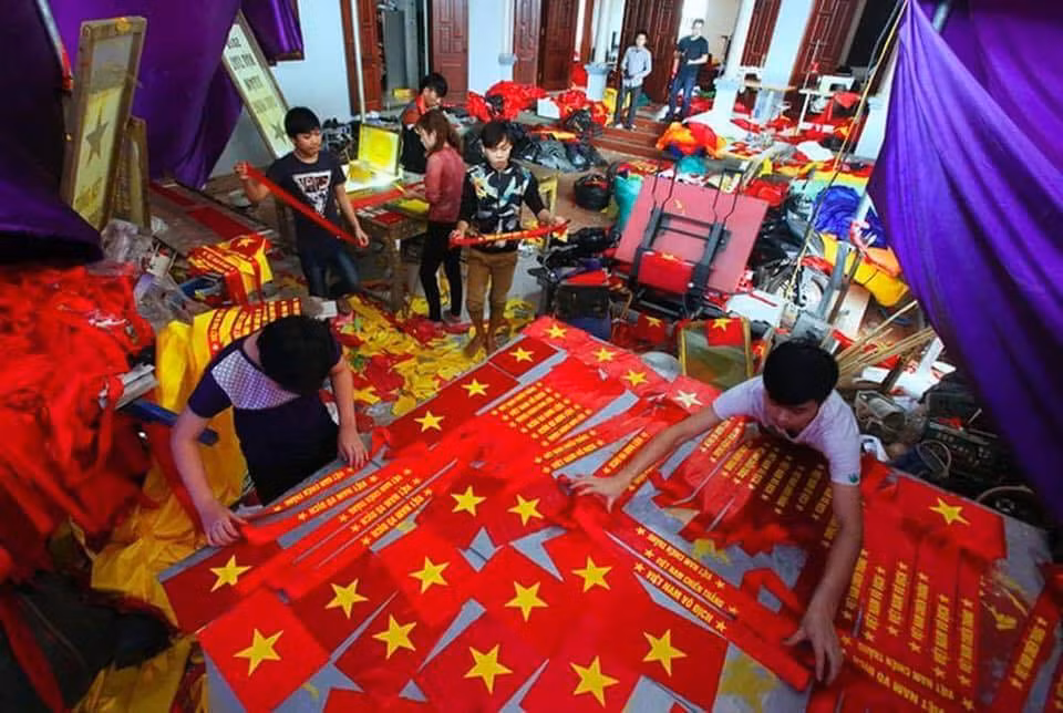 Không khí tất bật chuẩn bị băng rôn, cờ đỏ sao vàng bên trong một cơ sở sản xuất. Ảnh: Facebook.