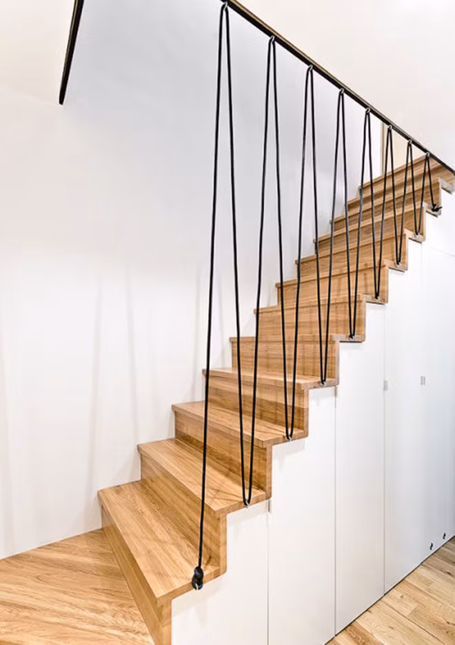 Cầu thang gỗ với lan can bằng dây cáp đen tạo điểm nhấn cho góc nhà thêm phần bắt mắt.
