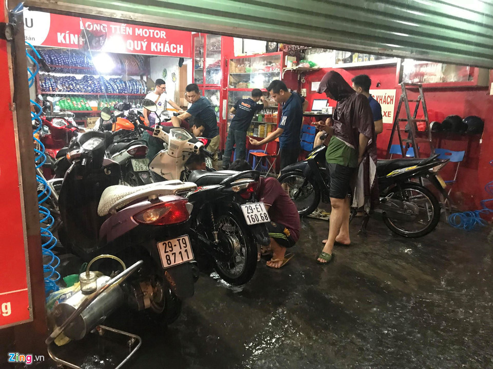 Một cửa hàng sửa xe máy trên phố Hoa Bằng (quận Cầu Giấy) bỗng dưng chật kín khách tới lau bugi, thay lọc gió sau khi bị nước ngập vào máy vì cố đi qua khu vực ngập sâu.