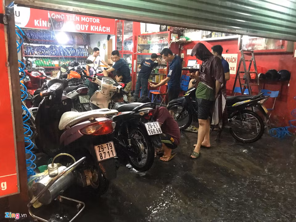 Một cửa hàng sửa xe máy trên phố Hoa Bằng (quận Cầu Giấy) bỗng dưng chật kín khách tới lau bugi, thay lọc gió sau khi bị nước ngập vào máy vì cố đi qua khu vực ngập sâu.