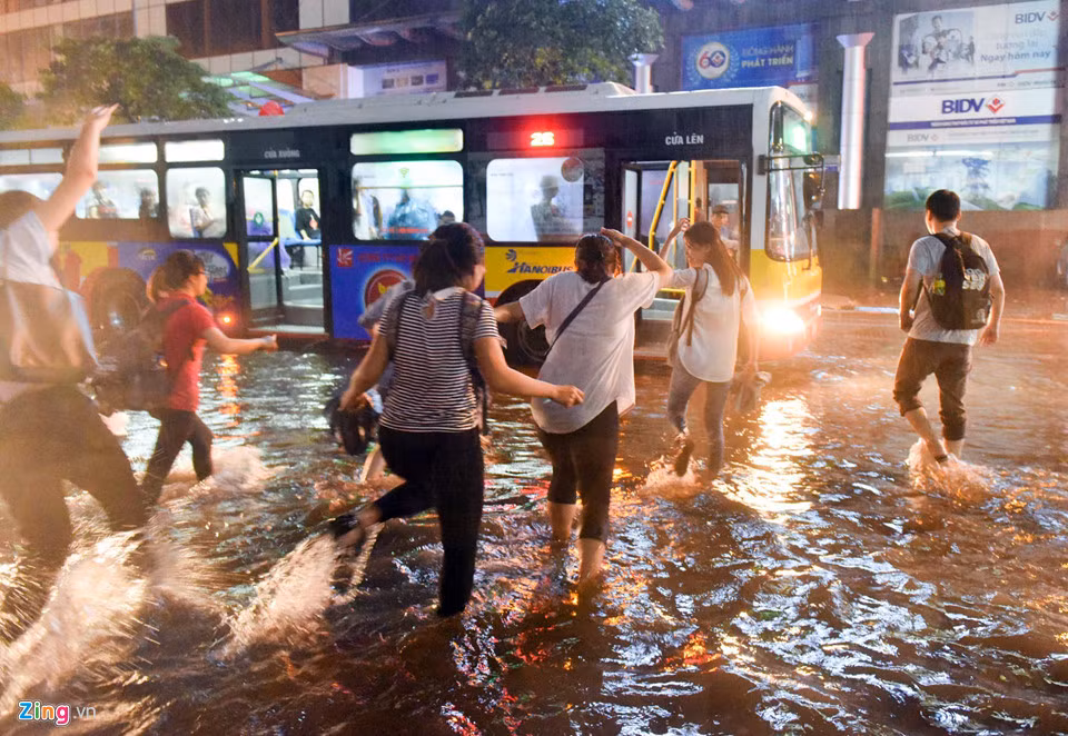 Lề phố Thái Hà bị ngập sâu, xe buýt không thể đỗ vào bến đành dừng giữa đường cho khách trèo lên.