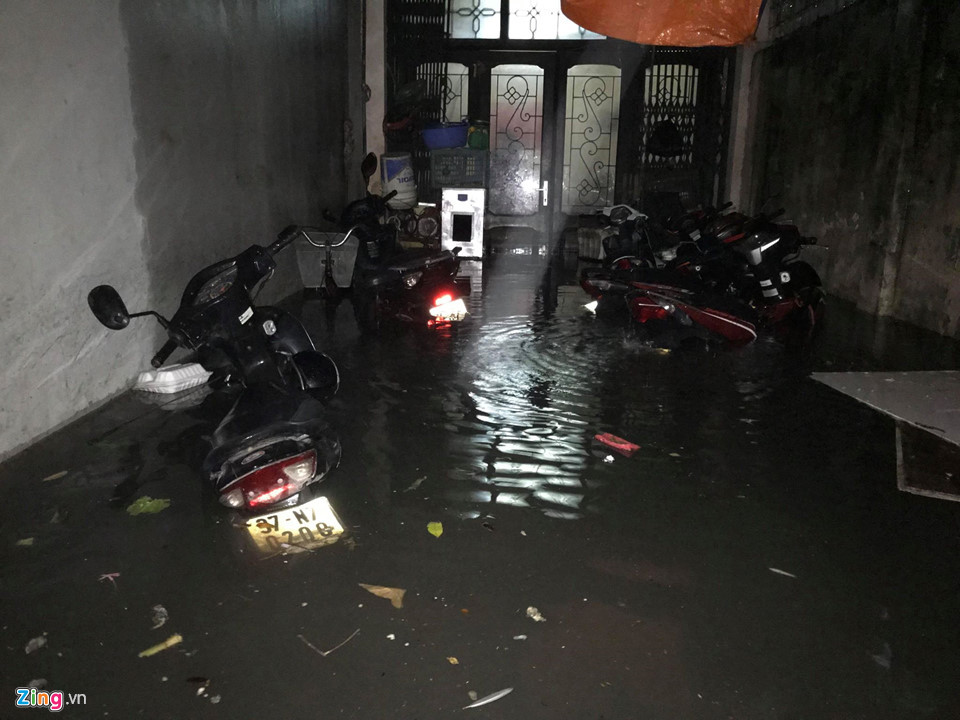 20h, mưa to trút xuống càng mạnh hơn, nhiều xe máy dựng trước cửa nhà bị ngập tới gần yên.