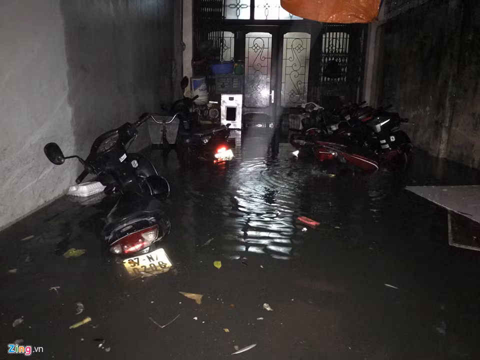 20h, mưa to trút xuống càng mạnh hơn, nhiều xe máy dựng trước cửa nhà bị ngập tới gần yên.