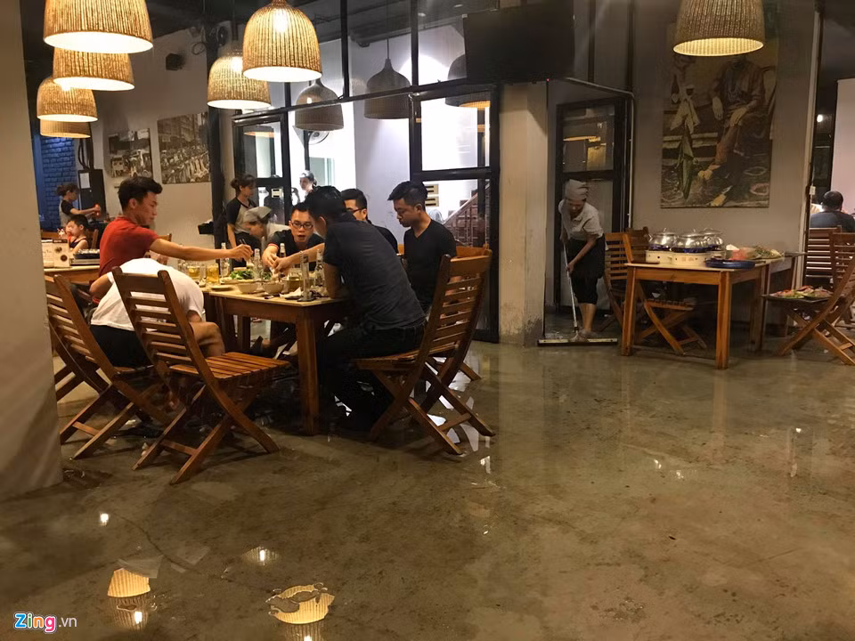 Tại phố Chùa Hà, một nhà hàng bị nước dâng cao tràn vào trong. Khách ngồi ăn uống co chân tránh ướt.