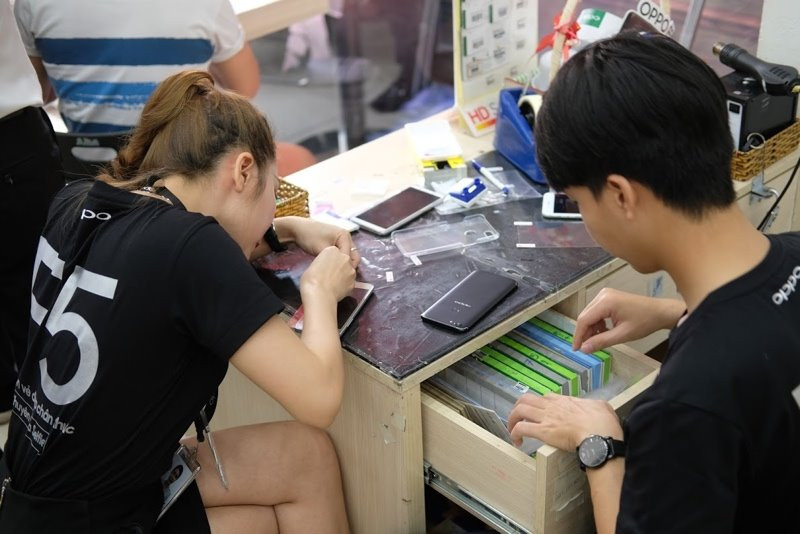 Nhân viên một siêu thị đang dán màn hình cho Oppo F5 vào ngày smartphone này mở bán - Ảnh: H.Đ