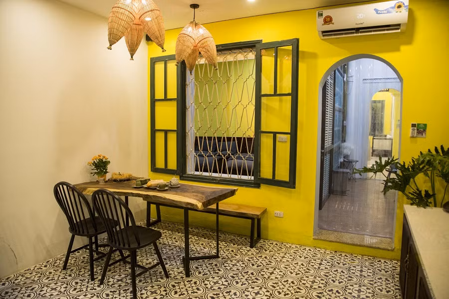 Bàn ăn mộc mạc được tô điểm bằng chiếc đèn chụp mang dáng dấp của chiếc đơm đánh cá, gợi nhắc ký ức thôn quê.