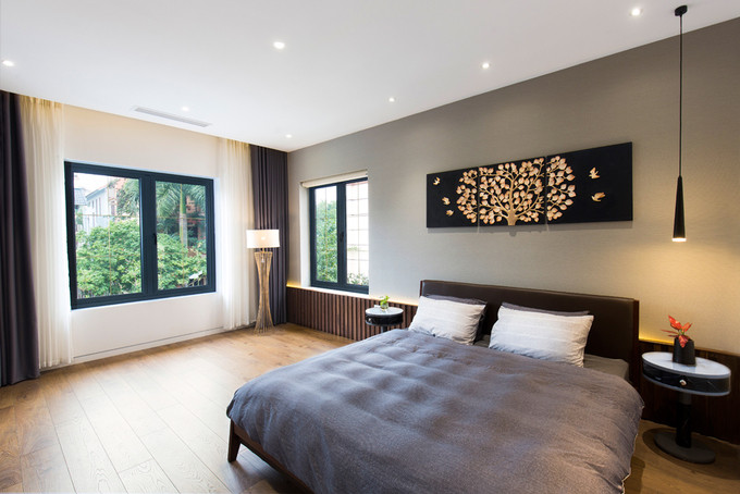 Phòng ngủ thoáng sáng với nội thất tối giản và nhiều cửa sổ lớn.