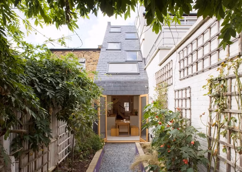 Do chiều ngang hẹp, nằm giữa các ngôi nhà cao tầng nên phần mái được thiết kế ngiêng và bố trí những tấm kính chịu lực trên bề mặt để lấy sáng. Ảnh: Homedit.