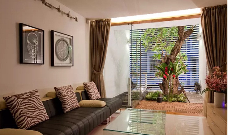 Phòng khách trên tầng lửng, có thể nhìn ra khoảng thông tầng xanh mát.