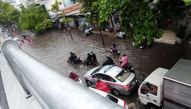 Người dân bì bõm lội nước qua khu vực cầu vượt Nguyễn Hữu Cảnh.