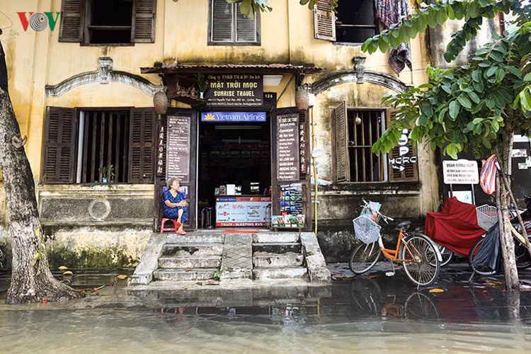 Một chủ cửa hiệu ngồi nhìn nước lũ lên từng phút.