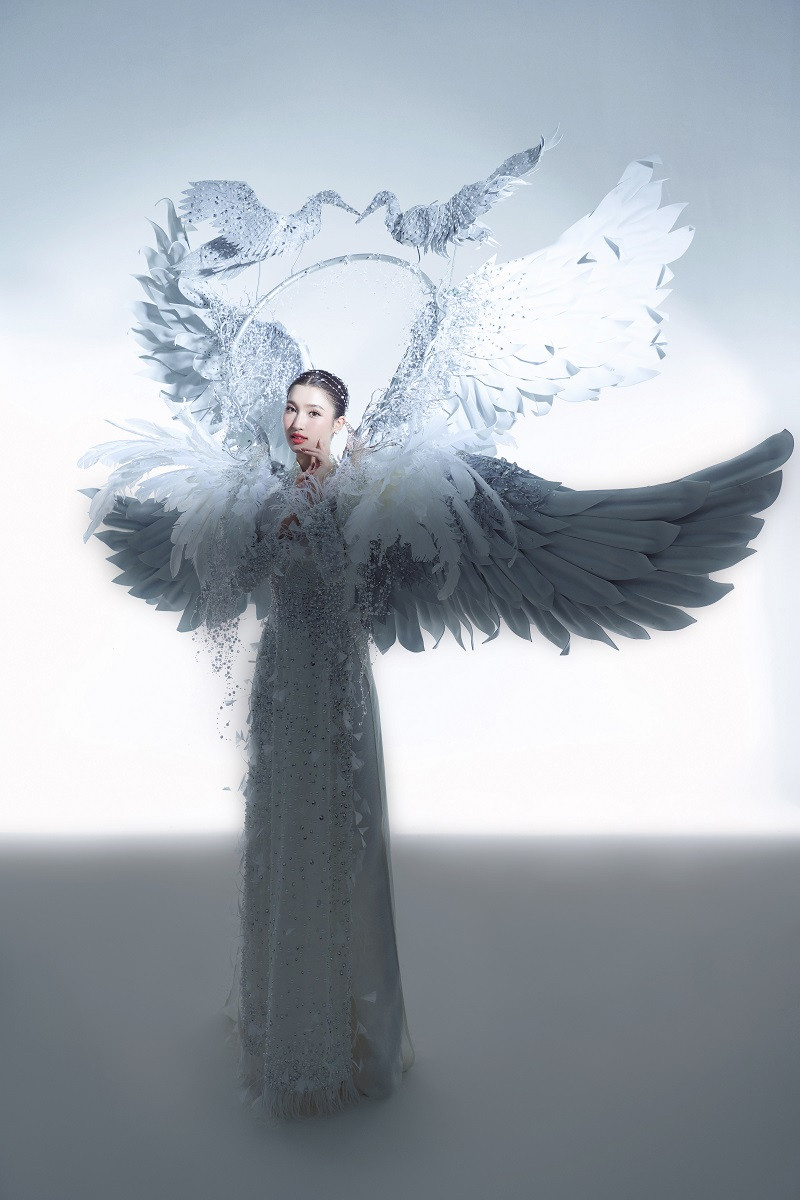 “Cò ơi” được thiết kế đẹp mắt, trung tâm là bộ áo dài truyền thống, đằng sau là hai chiếc cánh lớn và khung tròn có hai chú cò hướng mặt vào nhau. Các chi tiết được đính kết thêm kim tuyến, đá và dây ngọc giúp cho bộ trang phục thêm lấp lánh.