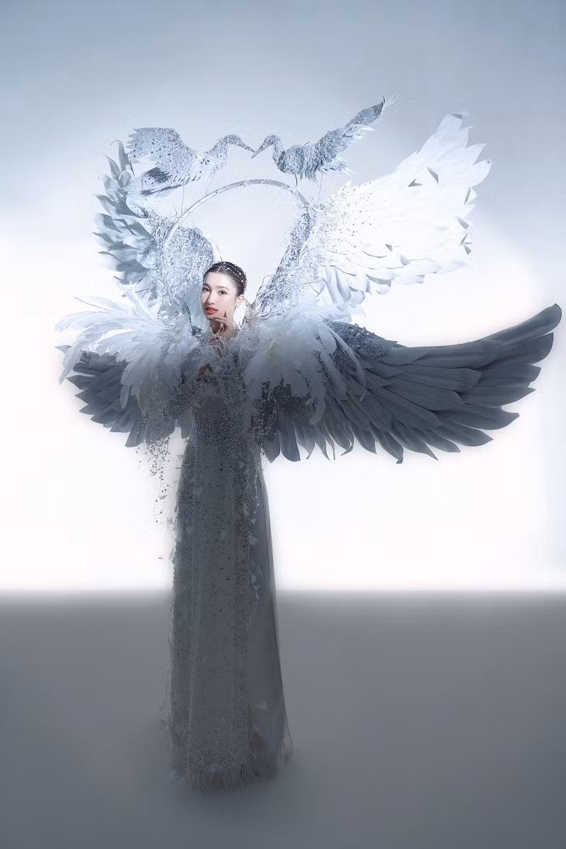 “Cò ơi” được thiết kế đẹp mắt, trung tâm là bộ áo dài truyền thống, đằng sau là hai chiếc cánh lớn và khung tròn có hai chú cò hướng mặt vào nhau. Các chi tiết được đính kết thêm kim tuyến, đá và dây ngọc giúp cho bộ trang phục thêm lấp lánh.