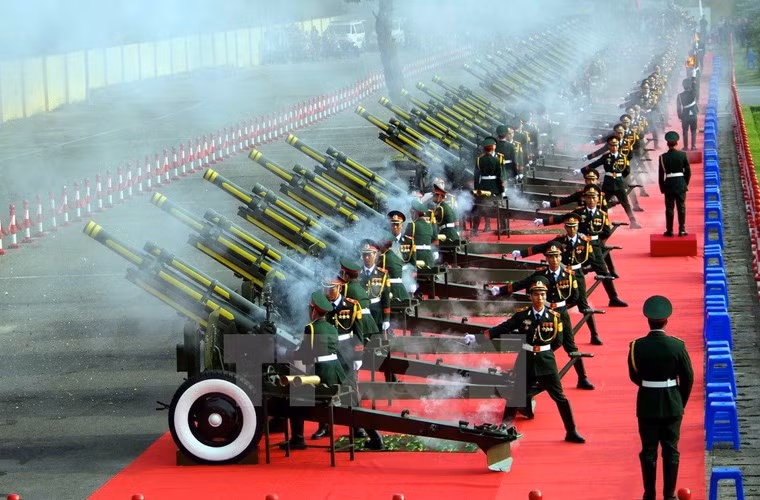 Đúng 7h5 phút, Quân nhạc cử Quốc thiều, đội nghi lễ thực hiện nghi lễ kéo cờ, các đồng chí lãnh đạo Đảng, Nhà nước, Mặt trận Tổ quốc Việt Nam, các vị đại biểu cùng toàn thể các lực lượng tham gia nghiêm trang thực hiện Lễ chào cờ. Cùng với lời hát quốc ca hùng tráng vang khắp Quảng trường Ba Đình là 21 loạt đại bác được bắn ra từ khu vực Hoàng Thành Thăng Long. Ảnh: TTXVN