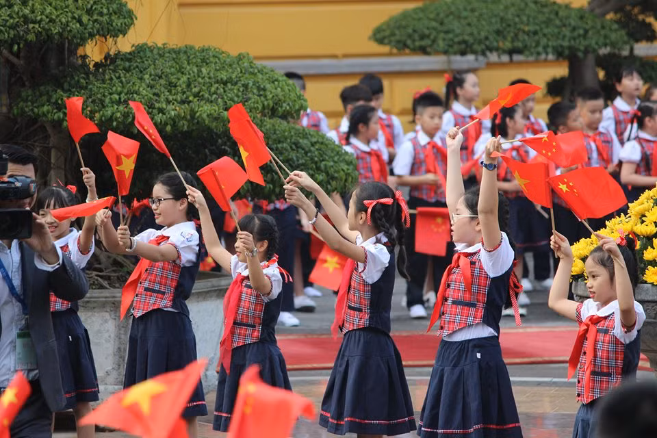 Đứng dọc hai bên là 200 cháu học sinh trường tiểu học Thăng Long (Hà Nội) cầm cờ hai nước Việt - Trung tung bay chuẩn bị chào đón Tổng Bí thư, Chủ tịch Trung Quốc Tập Cận Bình và đoàn ngoại giao Trung Quốc.