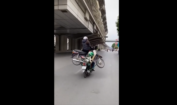 Người phụ nữ ngồi vắt vẻo trên xe không màng tới nguy cơ tai nạn có thể xảy đến trong tích tắc. Ảnh: Cắt ra từ clip