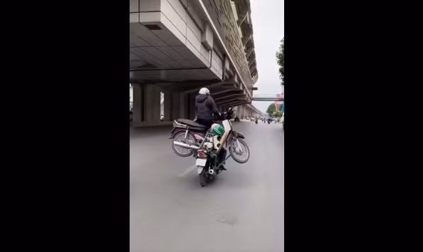 Người phụ nữ ngồi vắt vẻo trên xe không màng tới nguy cơ tai nạn có thể xảy đến trong tích tắc. Ảnh: Cắt ra từ clip