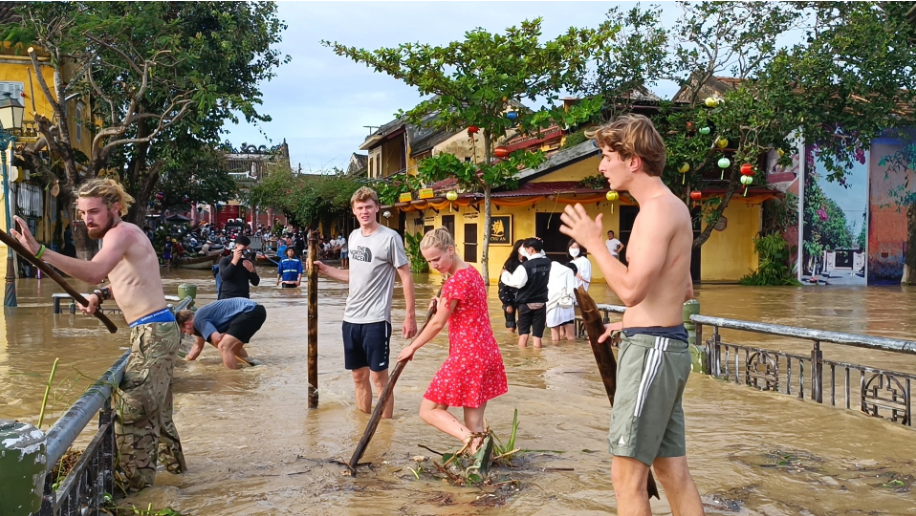 Nhìn thấy cảnh tượng rác từ khắp nơi theo dòng nước lũ tràn vào trung tâm thành phố và mắc lại trên các thành cầu, nhóm khách du lịch ngoại quốc đã không ngại nước lũ siết, nhanh chóng cùng nhau ra sức dọn rác làm sạch dòng nước đang chảy ở giữa lòng phố cổ.