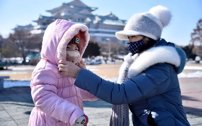 Người mẹ giúp con đeo khẩu trang trên đường phố Bình Nhưỡng ngày 6/2/2020.