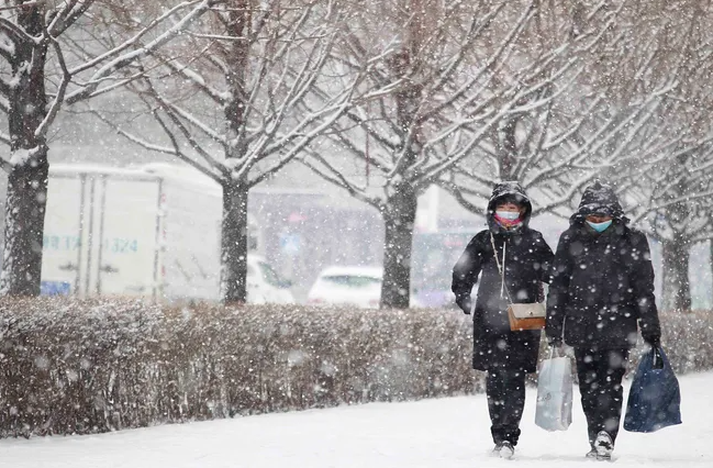 Người dân đi bộ dưới trời tuyết rơi ở Bình Nhưỡng, Triều Tiên, ngày 18/12/2021.