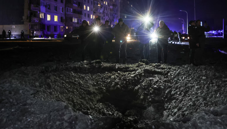 Người dân đứng cạnh một miệng hố xuất hiện sau vụ tấn công của Nga tại Kharkiv hôm 30/1.