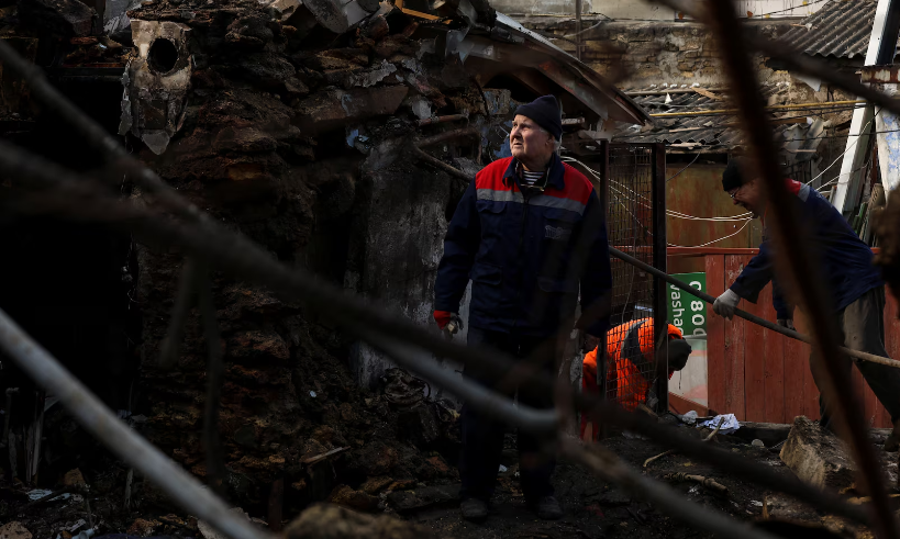 Các công nhân dọn dẹp đống đổ nát tại một khu dân cư bị tàn phá nặng nề ở Odesa hôm 24/2.