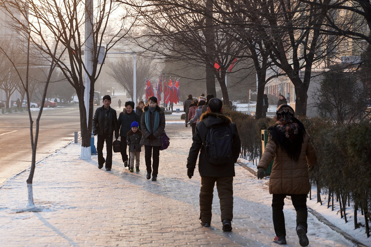 Người dân đi bộ trên con đường đầy tuyết ở Bình Nhưỡng vào một buổi sáng sớm mùa đông. Đây là khung cảnh đường phố buổi sáng điển hình ở trung tâm thủ đô của Triều Tiên vào một ngày mùa đông.