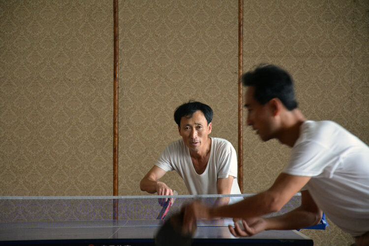 Hai người đàn ông chơi bóng bàn với nhau sau giờ làm việc ở thành phố Hamhung.