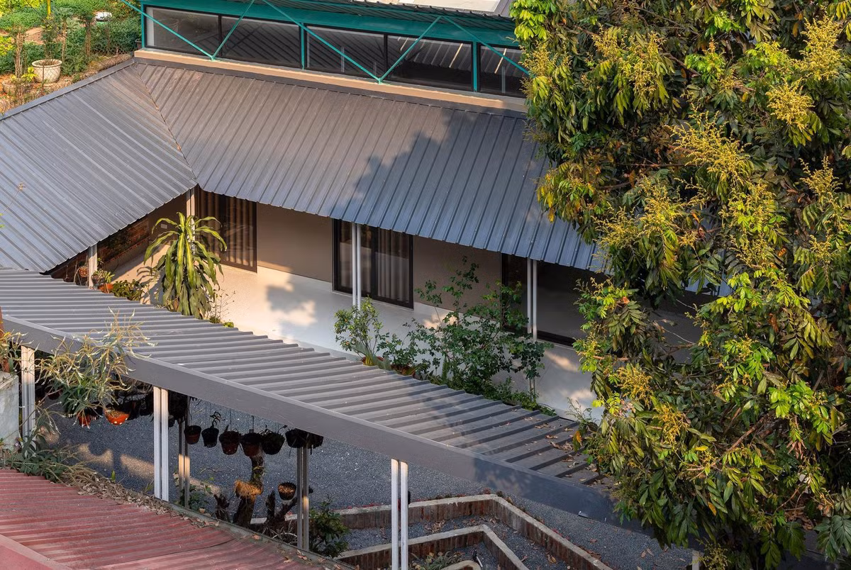 Một mái hiên bằng tôn được dựng lên xung quanh khoảng sân, kết nối với ngôi nhà, tạo ra vòng khép kín quanh sân để trồng hoa lan và cây cảnh.