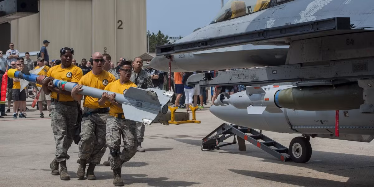 Các nhân viên kỹ thuật mặt đất đang ôm quả tên lửa AIM-9 để lắp lên tiêm kích F-16 trong hội thi lắp vũ khí nhanh tại căn cứ không quân Kunsan, Hàn Quốc. Ảnh: USAF.