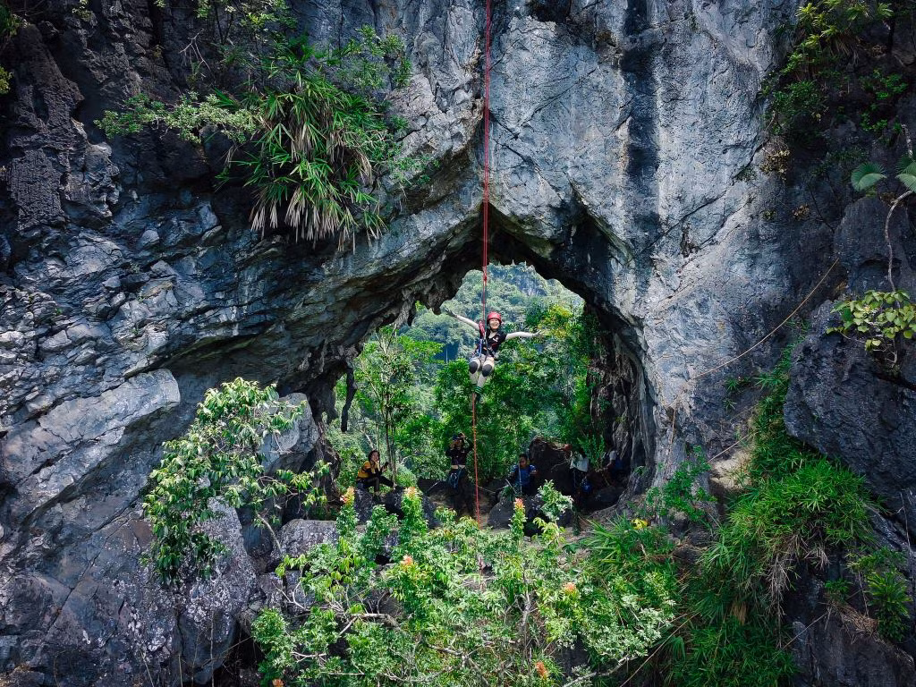 Du khách đu dây lơ lửng, check-in cùng “lỗ thủng” của núi. Từ đỉnh núi, du khách có thể ngắm nhìn toàn cảnh thung lũng Lân Ty và các ngọn núi xung quanh. Ảnh: Vietnam Expeditions