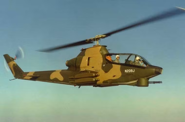 AH-1 ra đời trong bối cảnh lực lượng trực thăng Mỹ vất vả trong cuộc chiến với quân giải phòng miền Nam Việt Nam. Trực thăng UH-1 tuy cơ động cao, hỏa lực tương đối mạnh nhưng dễ bị tổn thương trước hỏa lực tầm thấp của bộ đội quân giải phóng miền Nam. Chính vì vậy, điều này đã thúc đẩy Bell Helicopter phát triển trực thăng chiến đấu theo yêu cầu của Quân đội Mỹ. Tháng 1/1965, Bell đã đầu tư 1 triệu USD nghiên cứu thiết kế mới và cho ra đời kiểu Bell 209 (trong ảnh) với hệ thống cánh quạt, động cơ của UH-1.