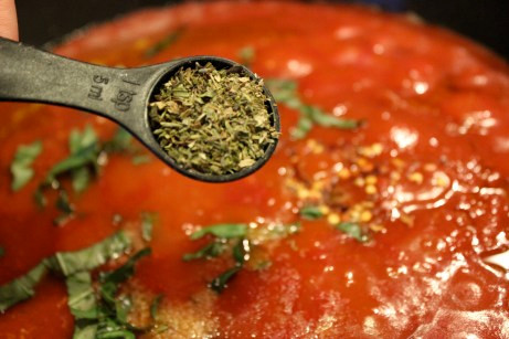 Tiếp theo lần lượt cho thêm muối, ớt, lá kinh giới oregano vào khuấy đều cho đến khi sôi.