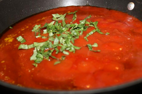 Cho sốt cà chua và cà chua nghiền vào nồi rồi cho thêm lá húng quế tươi.