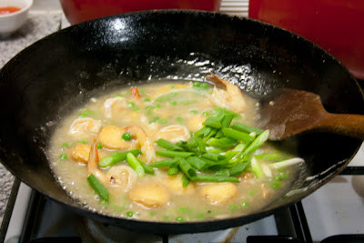 Sau đó cho tôm vào nấu khoảng hơn 1 phút nữa. Bột bắp pha với một ít nước rồi đổ vào và khuấy đều cho hỗn hợp sệt lại. Khi gần được thì đập trứng vào và khuấy đều để trứng không vón cục rồi cho hành lá vào. 