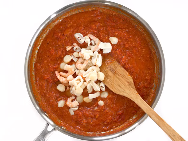 Cho toàn bộ số hải sản vào sốt cà chua.