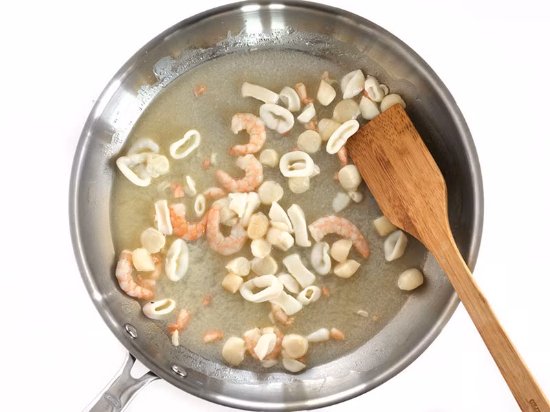 Cho khoảng 2 thìa bơ vào chảo to rồi bật bếp nóng vừa để bơ tan ra. Khi bơ bắt đầu sôi lên thì cho hải sản vào đảo, thấy tôm đã chuyển sang màu hồng và hải sản khác không còn trong suốt (khoảng 3-5 phút) thì tắt bếp. Chú ý không nấu hải sản quá kỹ, chỉ nấu sao cho hải sản vẫn mềm. Xúc hải sản ra bát và để sang một bên. 