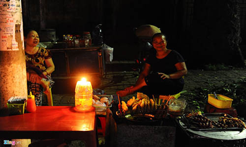 Một hàng bán bánh gối sử dụng nến để thắp sáng. Tuy vậy, hàng hôm nay bà chủ bị ế khách do ít người ra đường. 