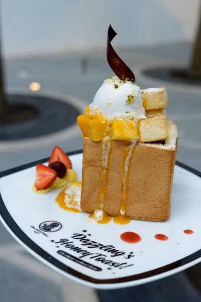 Bánh mì nướng mật ong trông khá bắt mắt bởi chiều dày ấn tượng của khoanh bánh mì, bên trên có kem tươi và kem lạnh. 